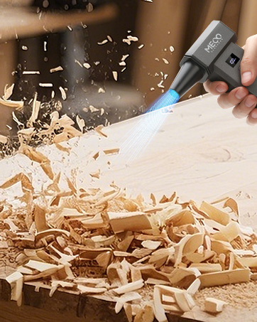 Handheld butane torch igniting over wood shavings on a workbench. Blue flame visible, with wood chips flying in the air from heat or airflow.