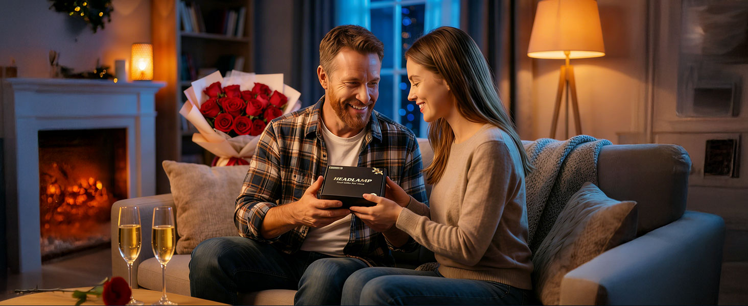 Couple exchanging gifts in cozy living room with fireplace, heart-shaped box visible, champagne glasses on table, warm ambient lighting.