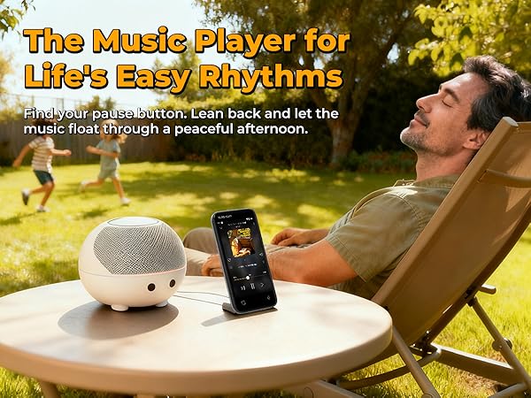 MP3 player on a table with a speaker, while a person relaxes in the yard on a sunny day