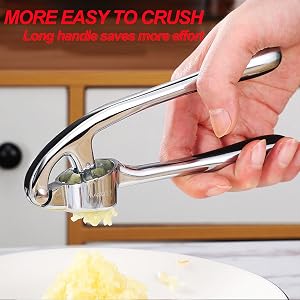 Text reads 'MORE EASY TO CRUSH'. Chrome garlic press being demonstrated crushing garlic clove over light-colored surface.