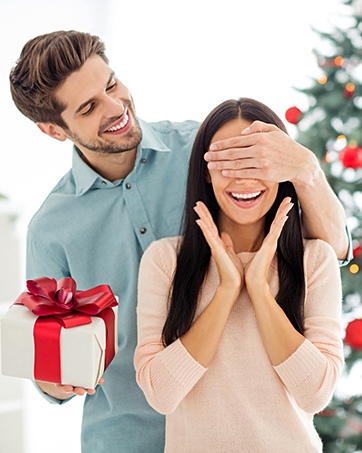 Three-panel sequence showing surprise gift presentation moment with red bow against winter holiday setting.