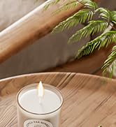 Tea light candle holder with bamboo or plant elements in a minimalist setting with natural wood surface.