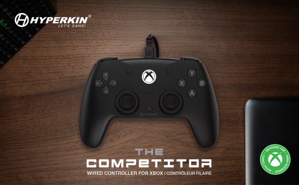 Black Hyperkin wired Xbox controller on wood surface with branding and Xbox compatibility seal.