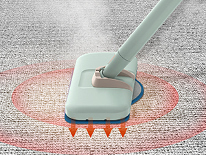 Light blue carpet cleaning head attachment with heating elements shown treating a red stain on gray carpet, with orange heat indicators visible beneath.