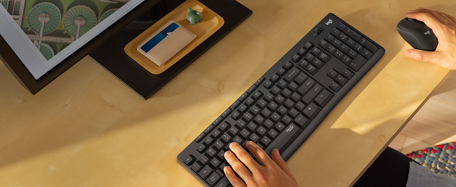 a man typing on the keyboard of mk295 wireless keyboard and mouse graphite combo