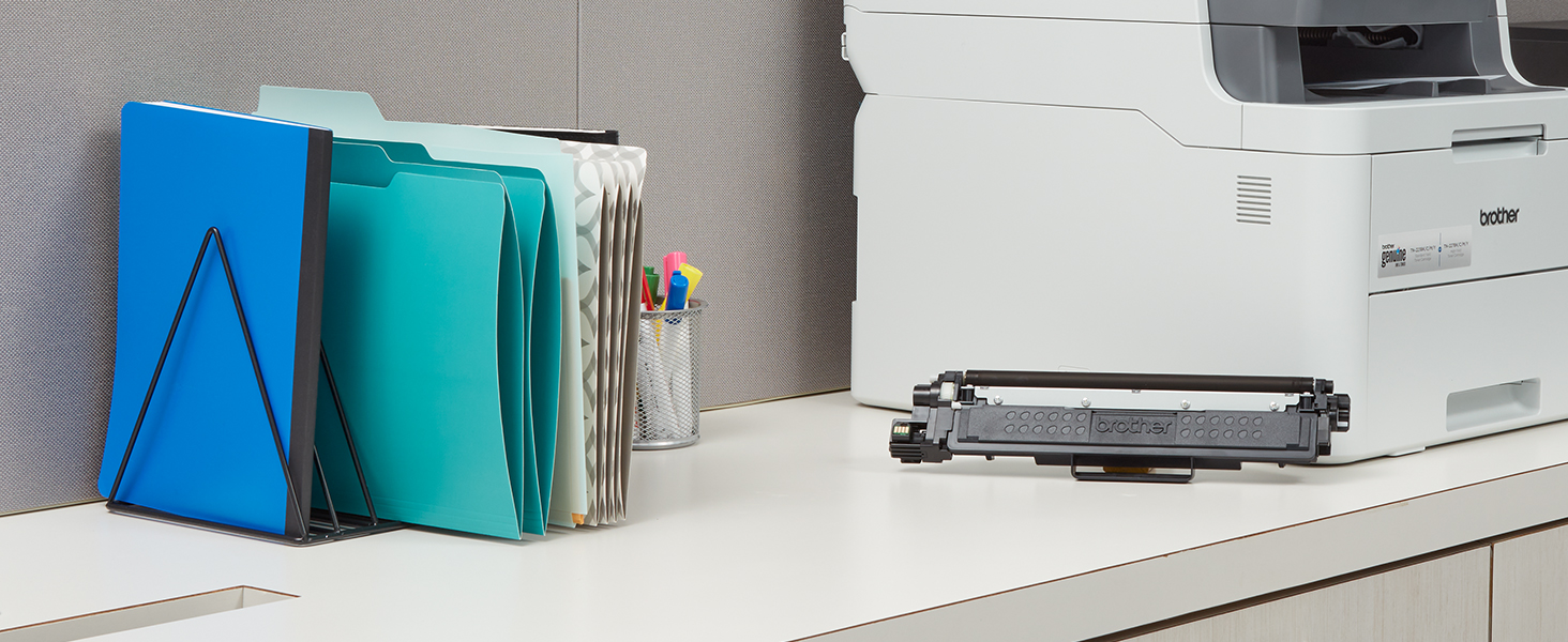 TN223BK Toner Cartridge Next to Printer