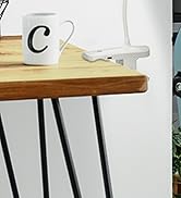 White desk power adapter or charging hub mounted underneath a wooden table surface with black metal legs. A white coffee mug visible on top.