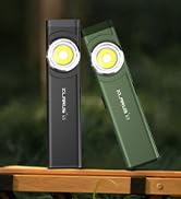 Two slim portable LED lights in black and olive green colors, displayed on wooden surface with bright illuminated ends.