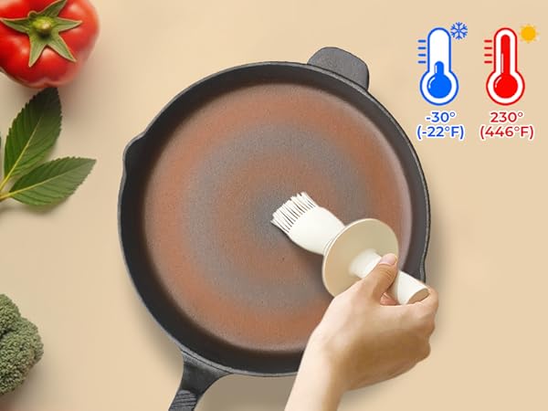 Round non-stick frying pan with temperature range icons showing -30°C to 230°C (-22°F to 446°F). Hand applying oil with a brush. Tomato and broccoli visible.