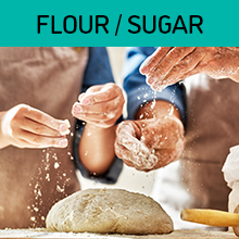 Closeup of two people in brown aprons sprinkling flour on a pile of dough