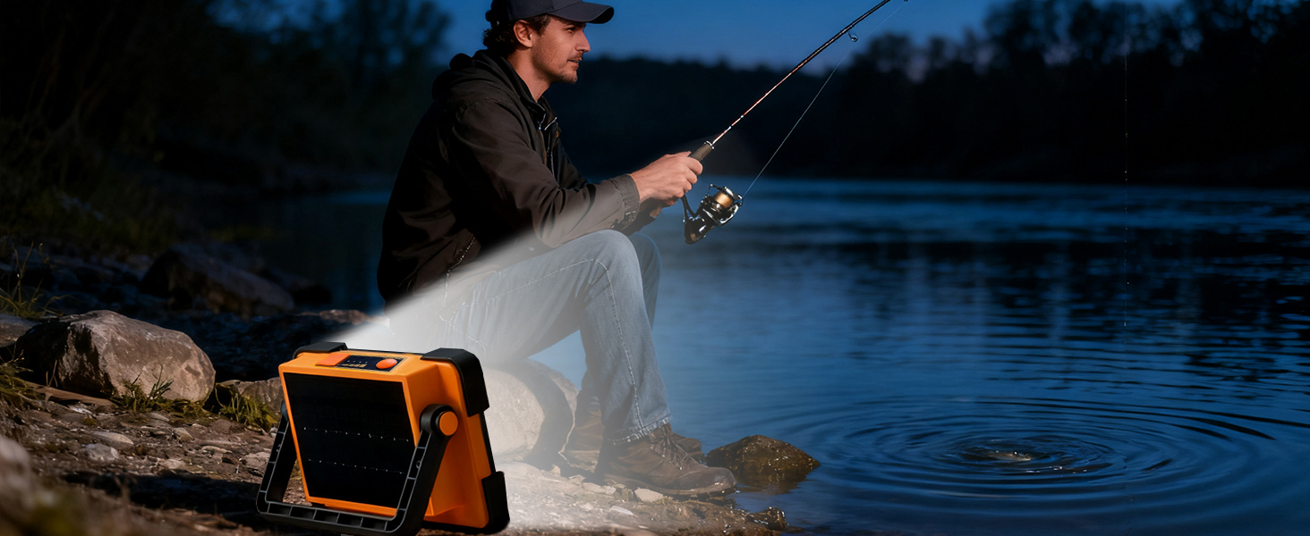Angler fishing at river at night with portable LED work light illuminating the bank