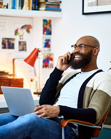 Lifestyle image of a man on the phone and sitting with a laptop on his lap
