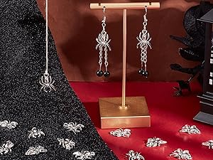 Jewelry display stand with dangling silver earrings on wooden T-shaped holder against dark background with decorative pattern.
