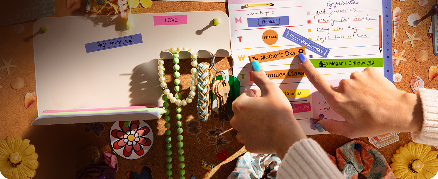 Person applying colorful Brother P-touch Btag reminder labels to calendar on form room cork board