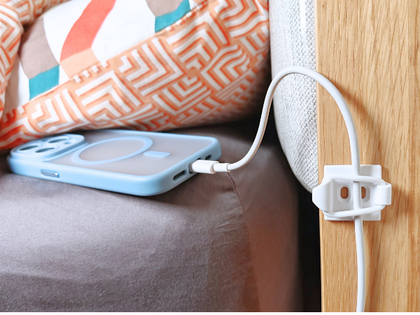Phone charging cable secured by bed.