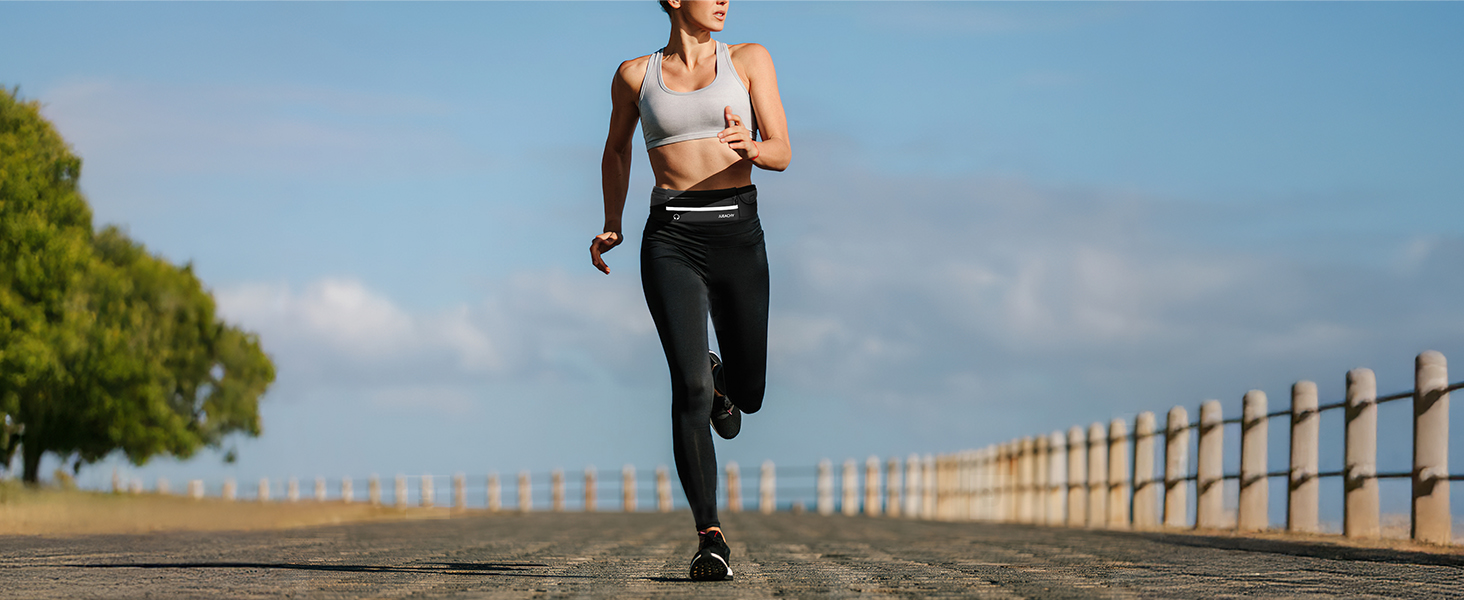 Athletic person jogging along wooden fence path against blue sky background, wearing workout attire and exercising outdoors.