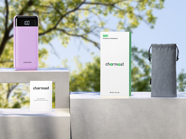 Outdoor product display featuring a pink power bank, product boxes, and a gray pouch. Items arranged on a light-colored surface with trees in the background.