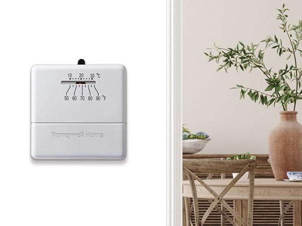 Manual thermostat on wall next to table with plant