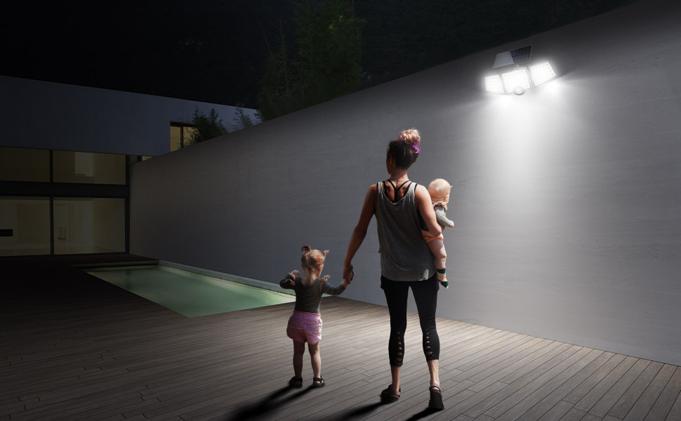 a woman and two children walking on a deck at night.
