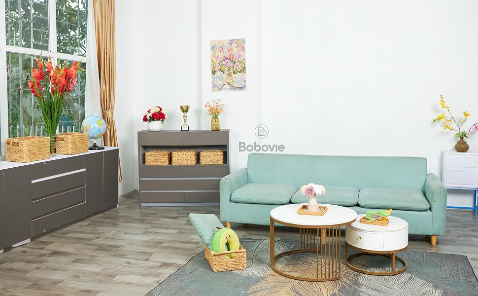 Cozy living room with teal sofa, floral art, and wicker baskets.