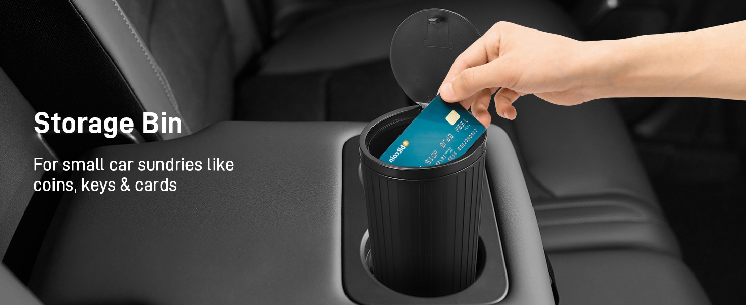 Black car storage bin labeled for coins, keys and cards, with teal-colored item being placed inside.