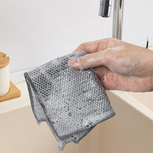 Close-up of a hand holding a grey textured cloth or sponge, wiping or cleaning a surface. The cloth has a honeycomb-like pattern.