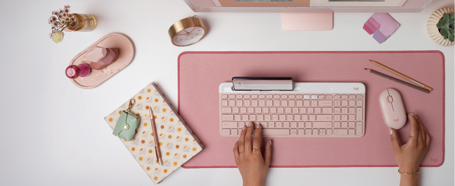 a woman using k585 slim compact wireless rose keyboard and m350 pebble shaped cordless pink mouse