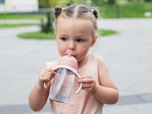 baby girl sipping out of a sippy cup outside