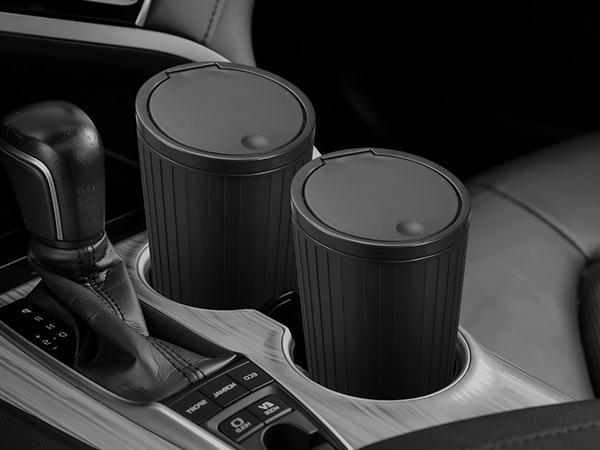 Two black cylindrical cup holders in a car's center console, positioned next to the gear shift.