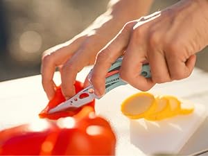 Photo shows person cutting a tomato with the Skeletool CX