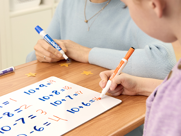girl doing math homework on dry erase board
