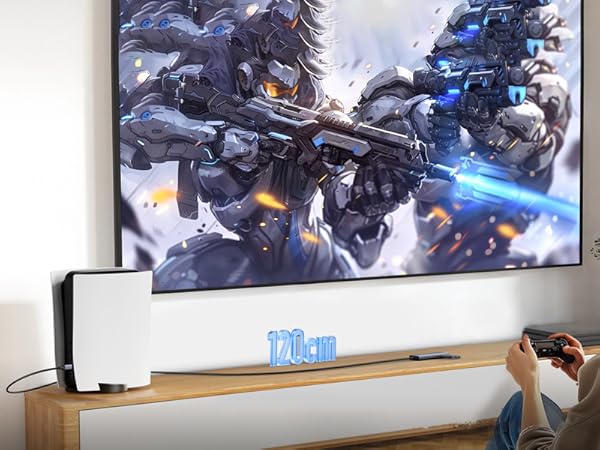 Gaming setup showing large wall-mounted display with sci-fi battle scene, white gaming console on wooden media unit, and controller in use.