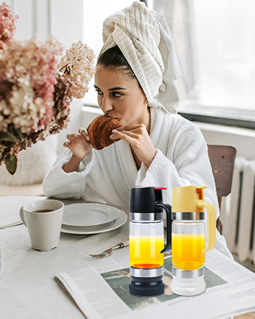 Two portable glass water bottles with citrus infuser chambers. One has a black lid, the other yellow. Bottles contain yellow liquid, likely lemon-infused water.