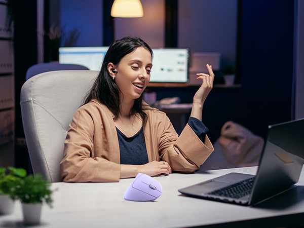 a woman sitting at a desk with a laptop and a phone in her hand