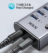 Close-up of a USB hub with multiple ports. Text indicates '7 USB 3.0' and 'Fast Charged' features.