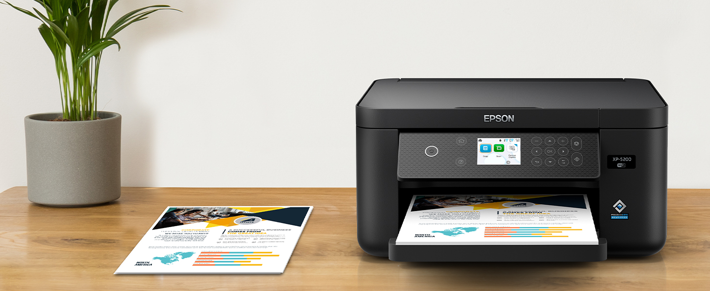 Stack of colorful printed flyers and black Expression Home XP-5200 printer sitting on desk.