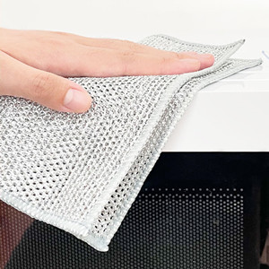 Close-up of a hand lifting a corner of a white textured microfiber cloth against a dark surface.
