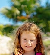 a little girl with red hair smiling at the camera.