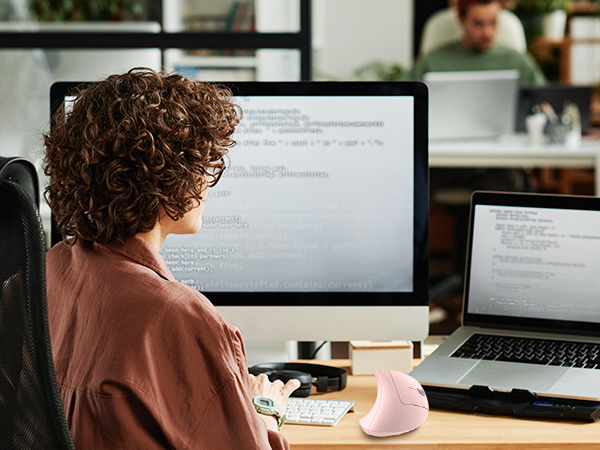 a woman sitting at a desk with a computer and a monitor.
