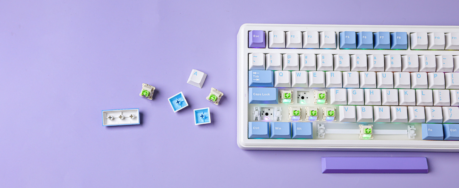 White computer keyboard with blue accent keys on purple background. Small, colorful cube-shaped keycaps with designs scattered nearby, some on the keyboard.