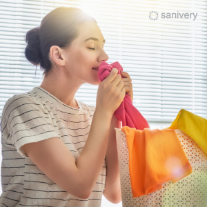 a woman is smelling fresh colorful clothes