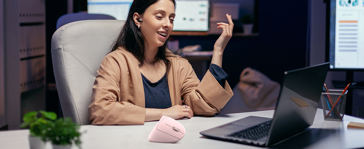 a woman sitting at a desk with a laptop and a mouse