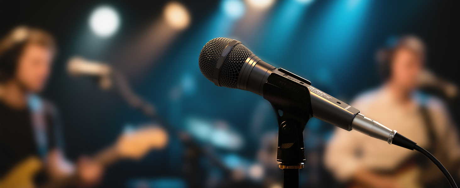 Close-up of a professional microphone on stage with blurred performers in the background, stage lighting creating atmospheric bokeh effects.