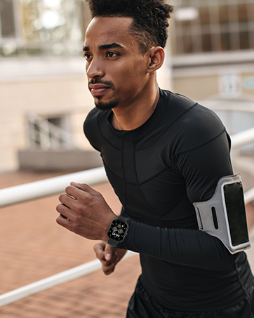 Athletic wear demonstration showing black compression shirt and smartphone armband holder during outdoor workout.