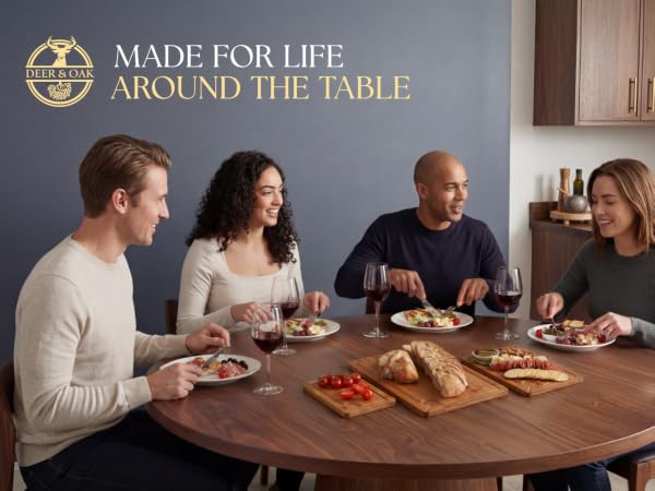 Text reads "MAKE LIFE AROUND THE TABLE". Multiple people seated at wooden table sharing meal and conversation together indoors.