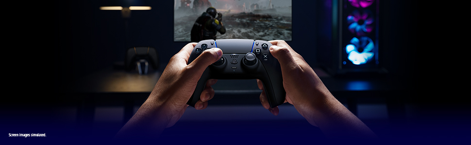 Hands holding a controller before a dim monitor with an action game and a colorful PC tower behind.