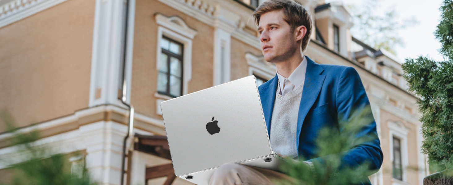 Silver MacBook laptop being used outdoors against architectural backdrop, displaying slim profile and characteristic aluminum design.