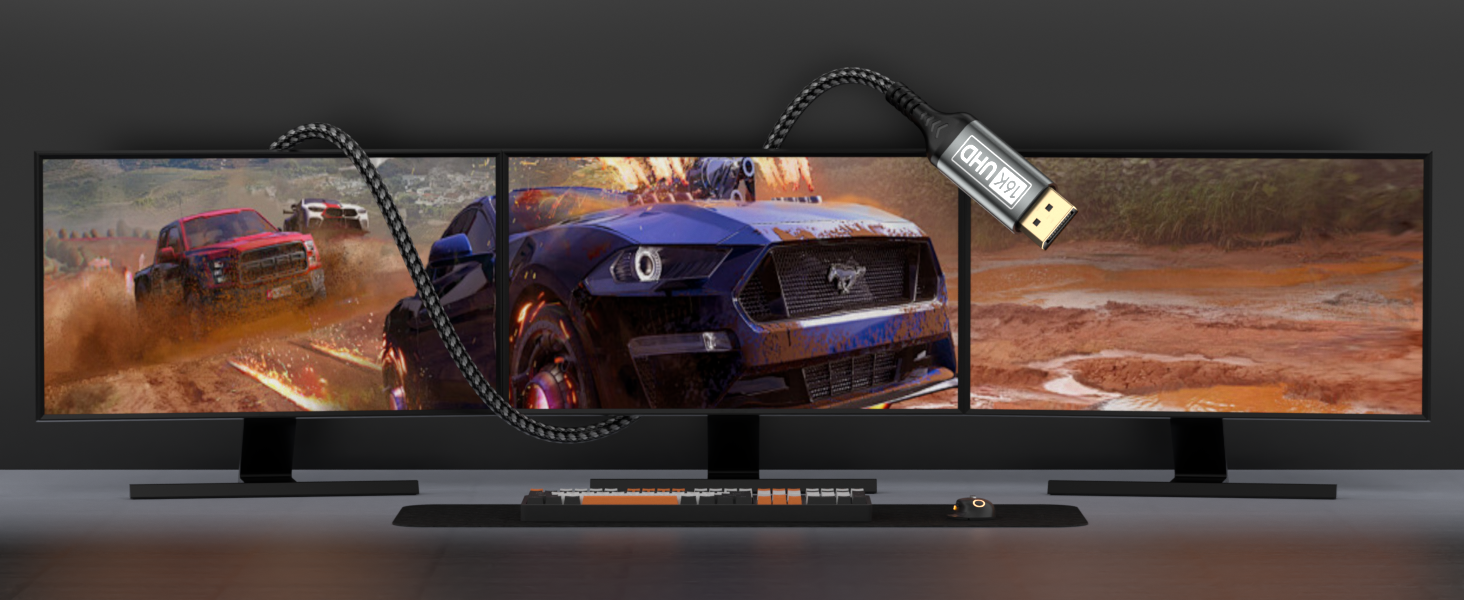 Three connected gaming monitors displaying a racing game scene with cars on a dusty track. A USB cable connects to the setup, suggesting PC compatibility.