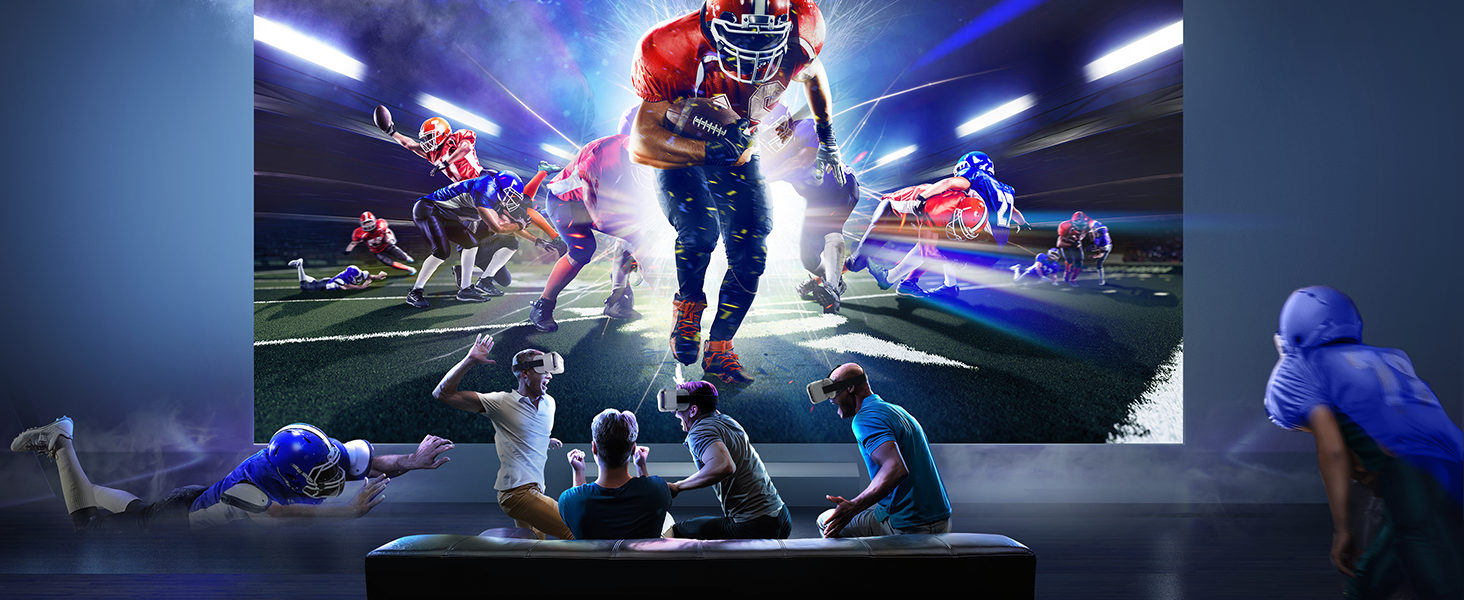 Gaming or esports setup showing large display with dynamic football gameplay scene, with multiple viewers watching in darkened room environment.