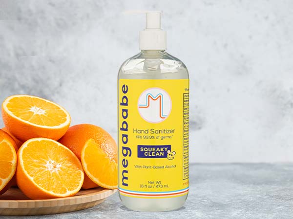 Hand Sanitizer on grey background next to oranges.